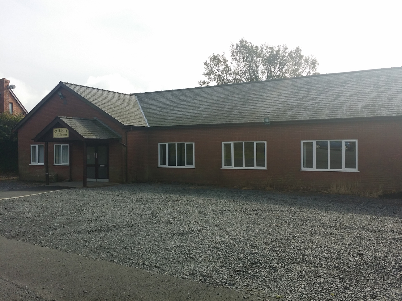 A view showing the front of the village hall with the car park in the foreground, taken from slightly left of centre